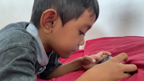 Un-Niño-Asiático-De-4-Años-Jugando-En-Su-Teléfono-Inteligente-Mientras-Está-Acostado-En-La-Cama
