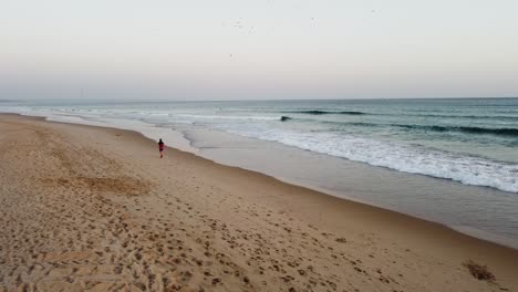 Luftaufnahme-Einer-Person,-Die-Bei-Sonnenuntergang-Am-Strand-In-Costa-Da-Caparica,-Portugal,-Spaziert