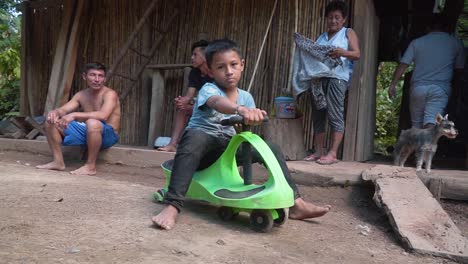 Kind-Spielt-Auf-Seinem-Grünen-Wackel-Plasmaauto-In-Der-Nähe-Seiner-Freunde,-Stadt-Huicungo,-Peru
