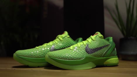 Grüne-Nike-Kobe-6-Protro-Grinch-2020-Schuhe,-Gefilmt-Auf-Einem-Braunen-Tisch-Mit-Dunklem-Hintergrund