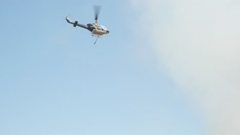 Fire-fighting-helicopter-flying-over-house-and-heading-to-grass-fire