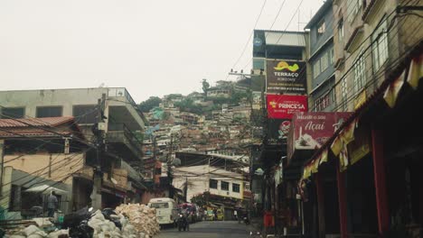 POV-Fahrt-Auf-Der-Straße-In-Richtung-Rocinha-Favela-Auf-Einem-Hügel-In-Rio-De-Janeiro,-Brasilien-–-Armut-Mit-Ungeschützten-Kabelbäumen-über-Der-Straße