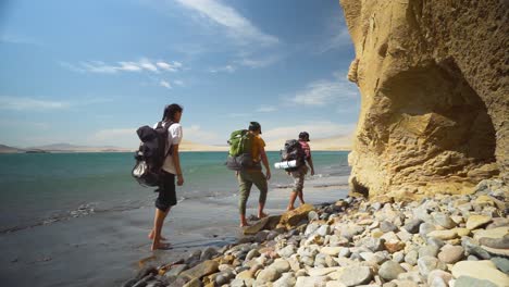 Campers-Walking-On-Sandy-Beach-Noticing-Huge-Rock-Formation,-California