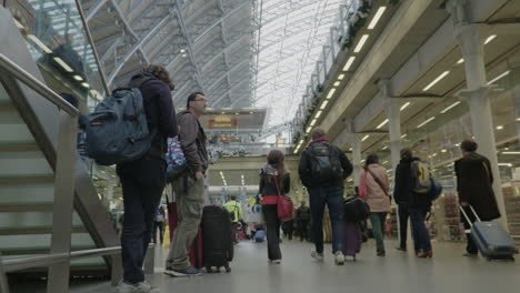 Statische-Aufnahme-Von-Zwei-Wartenden-Reisenden,-Die-Zusehen,-Wie-Viele-Menschen-An-Einem-Geschäftigen-Internationalen-Bahnhof-St.-Pancras-In-London-Vorbeigehen
