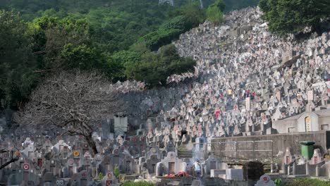 Vista-De-Un-Cementerio-Lleno-De-Gente-Durante-El-Festival-Chung-Yeung,-Mientras-La-Gente-Visita-Y-Quema-Ofrendas-Frente-A-Las-Tumbas-De-Sus-Familiares-Fallecidos-Como-Señal-De-Recuerdo-Y-Respeto.