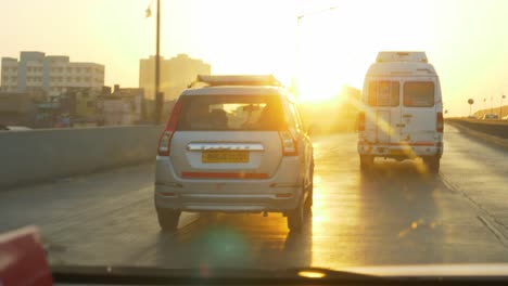 Driving-a-car-on-the-Mumbai-highway-towards-Panvel,-Lonavala,-Pune-at-beautiful-sunrise-with-Mumbai-skyline-buildings-in-view,-Point-of-View-shot