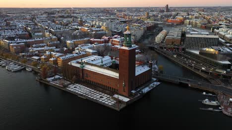 Aerial-footage-moving-away-from-the-City-Hall-of-Stockholm,-Sweden,-at-Sunset