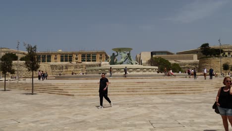 Tourists-Around-The-Triton-Fountain-In-Valletta,-The-City-Gate-In-The-Background