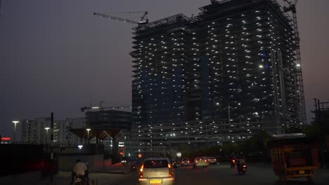 Toma-De-Punto-De-Vista-De-Montar-A-Caballo-Por-Las-Calles-De-La-Ciudad-De-Alta-Tecnología-De-Hyderabad-Con-Edificios-Y-Rascacielos-En-Construcción-Iluminados-Con-Luz-Nocturna