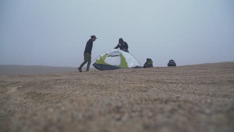 Tiro-Inclinado-De-Una-Caravana-Montando-Una-Tienda-De-Campaña-Para-Acampar-En-El-Desierto-De-Lima,-Perú