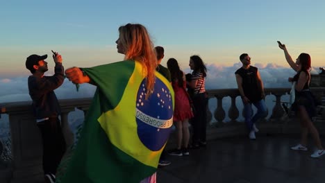 Female-tourist-holding-Brazilian-flag-posing-for-the-photograph-from-Christ-the-Redeemer-Point-Of-View-on-top-of-Corcovado-Mountain