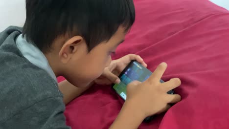 A-4-year-old-asian-boy-playing-games-on-his-smartphone-while-lying-in-bed