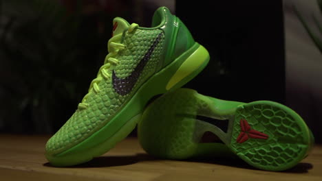 Grüne-Nike-Kobe-6-Protro-Grinch-2020-Schuhe,-Gefilmt-Auf-Einem-Braunen-Tisch-Mit-Dunklem-Hintergrund