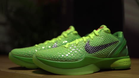 Zapatos-Nike-Kobe-6-Protro-Grinch-2020-Verdes-Filmados-Sobre-Una-Mesa-Marrón-Con-Fondo-Oscuro