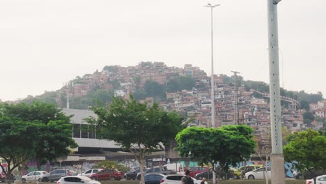 Wide-shot-of-traffic-on-road-in-Rio-de-Janeiro-with-Favela-Rocinha-located-ion-mountain-in-Background---Slow-motion