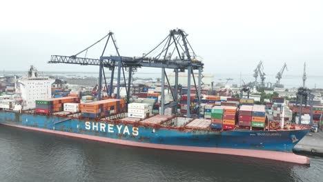 Aerial-View-Of-Cargo-Container-Ship-Docked-At-Terminal-Beside-Gantry-Cranes-At-Karachi-Port-Trust-Terminal