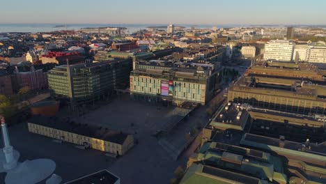 Aerial-view-towards-the-Kamppi-shopping-mall,-on-a-sunny,-summer-morning-sunrise,-in-Helsinki,-Finland---dolly,-drone-shot