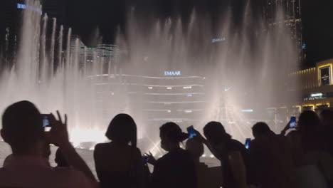 Touristen-Mit-Smartphones-Beobachten-Die-Dubai-Fountain-Show-Im-Mai-2021-In-Den-Vereinigten-Arabischen-Emiraten-Vor-Dem-Burj-Khalifa-Bei-Nacht