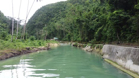 Flying-low-over-creek-towards-isolated-Cabin-hidden-in-lush-tropical-jungle