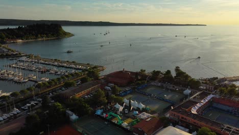 Drone-aerial-forward-slow-smooth-moving-flying-view-of-Portoroz-with-boats-in-sea-in-yellow-sunset-light,-Slovenia
