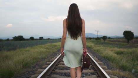 Model-in-summer-dress-slow-walking-on-train-track---Slow-motion-medium-follow-shot