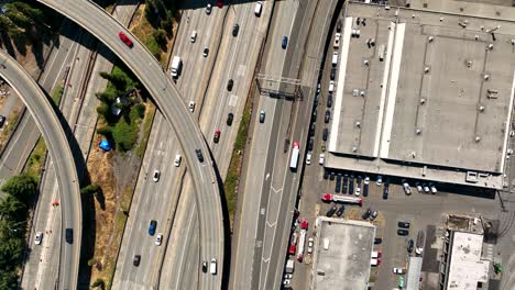 Top-down-drone-shot-of-cars-driving-on-the-freeway-through-Seattle's-Industrial-District