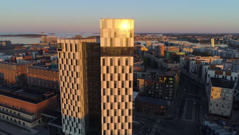 Aerial,-drone-shot-of-the-Clarion-Hotel,-on-a-sunny-morning,-during-sunrise,-in-Jatkasaari,-Helsinki,-Finland