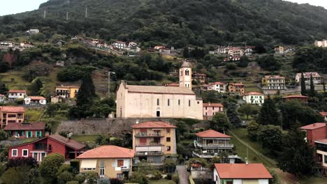 A-church-looks-over-the-coastline-of-Lake-Como-in-Domaso,-Italy