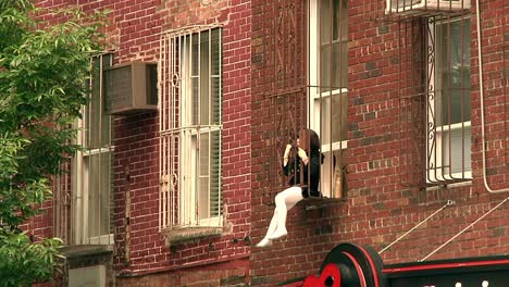 Young-Girl-Swinging-Her-Legs-From-Window-Safety-Cage-In-Brooklyn,-New-York