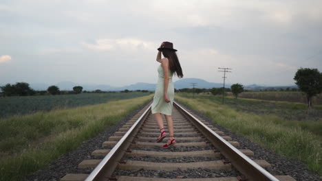 Follow-Me-Concept-Model-walking-on-train-track-at-dusk---Follow-slow-motion-wide-shot
