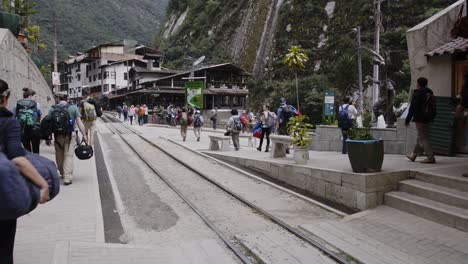 People-walking-near-the-leaving-train-from-Cusco-to-Machu-Picchu,-Peru