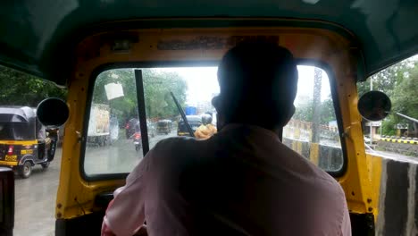 View-Behind-A-Tuk-Tuk-Driver-Travelling-On-The-Street-In-Mumbai,-India-On-A-Rainy-Weather---Passenger's-POV-Shot