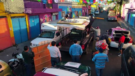 Dolly-in-flyover-of-a-group-of-people-mounting-and-securing-religious-pictures-in-a-black-van-in-the-carnivals-of-Iztapalapa,-CDMX,-Mexico