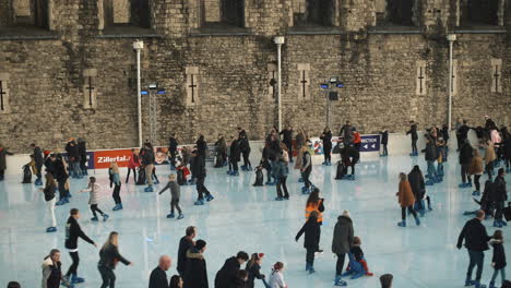 Crowd-of-people-ice-skating-on-an-outdoor-public-ice-rink-near-London-Tower-winter-in-UK
