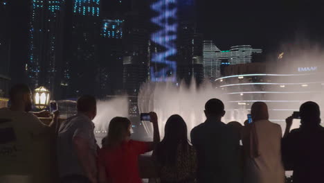 Touristen-Mit-Smartphones-Beobachten-Die-Dubai-Fountain-Show-Im-Mai-2021-In-Den-Vereinigten-Arabischen-Emiraten-Vor-Dem-Burj-Khalifa-Bei-Nacht