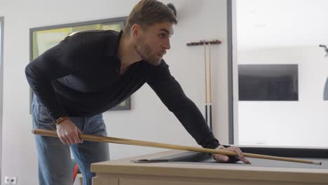 Slow-motion-shot-of-a-young-man-playing-pool-and-striking-the-ball