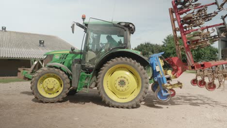 John-Deere-Traktor-Mit-Aufgedrehtem-Pflug,-Der-Sich-Auf-Dem-Bauernhof-Auf-Dem-Boden-Dreht