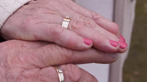 Close-up-of-the-joined-hands-of-a-newly-wed-elderly-couple-with-the-womans-hand-placed-on-top-of-the-mans-showing-off-the-rings