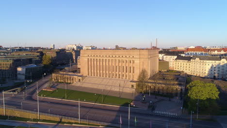 Aerial-view-of-the-Parliament-of-Finland,-sunny,-summer-morning-sunrise,-in-Toolo,-Helsinki---Pull-back,-drone-shot