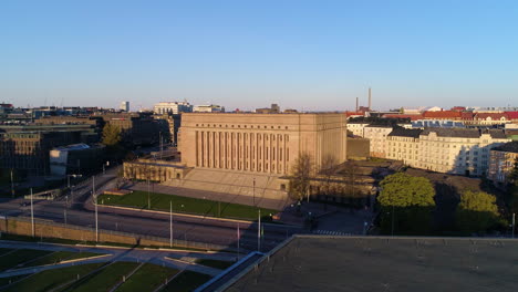 Approaching-Aerial-view-of-the-sunlit-Parliament-of-Helsinki,-sunny,-summer-morning-sunrise,-in-Toolo,-Helsingfors,-Uusimaa,-Finland---Dolly,-drone-shot