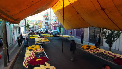 Bird's-eye-view-dolly-in-protective-tents-over-a-group-of-flower-arrangements-at-the-carnival-in-Iztapalapa,-CDMX,-Mexico