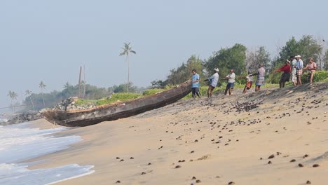 Local-people-pulling-traditional-fishing-nets,-Kappil-Beach,-Varkala,-India