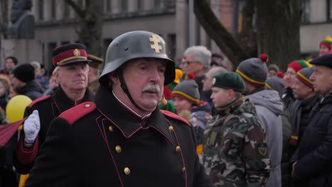 Slowmotion-track-of-a-retired-veteran-with-a-moustache-marching-in-full-uniform-in-a-parade-on-the-streets-of-Kaunas,-Lithuania