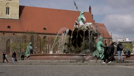 Touristen,-Die-Am-Neptunbrunnen-In-Berlin-Vorbeigehen,-Mit-Der-Marienkirche-Im-Hintergrund