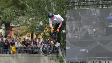 With-unwavering-confidence,-the-young-man-fearlessly-performs-awe-inspiring-stunts-on-his-bicycle-at-great-heights-in-the-skate-park,-successfully-nailing-each-trick-with-precision-and-expertise