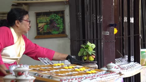 Zeitlupe-Einer-Thailändischen-Frau-In-Traditioneller-Tracht,-Die-Süßigkeiten-In-Einem-Außenladen-Im-Offenen-Museum-Der-Antiken-Stadt,-Erawan,-Thailand-Verkauft