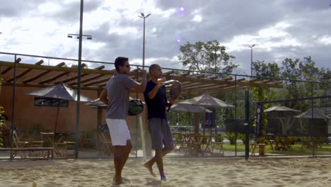 Zwei-Spieler-Geben-Sich-Nach-Einem-Beach-Tennis-Match-Gegenseitig-Ein-High-Five