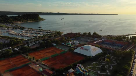 Drone-aerial-forward-slow-moving-flying-view-of-Portoroz-with-boats-in-sea-in-yellow-sunset-light,-Slovenia