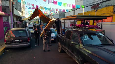 Group-of-people-carefully-mounting-pictures-on-a-black-van---Colorful-streets-of-Iztapalapa,-CDMX,-Mexico
