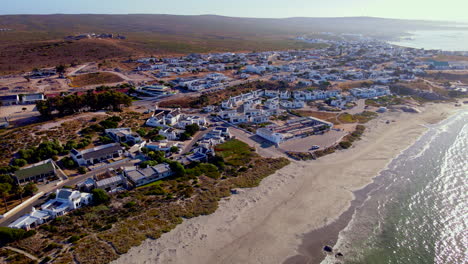 High-angle-aerial-over-scenic-coastal-fishing-village-of-Paternoster,-West-Coast